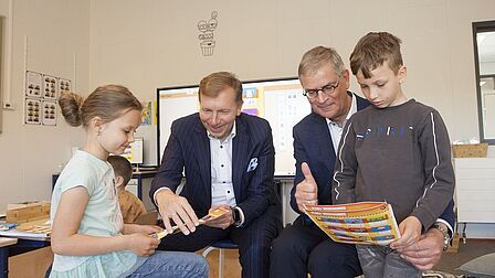Burgemeester Gert-Jan Kats en wethouder Marco0 Verloop kijken mee met Oekraïense kinderen in taalschool Pimpelmees. 