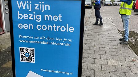 Op de foto staat een stoepbord met daarop de tekst: "Wij zijn bezig met een controle. Waarom we dit doen lees je op www.veenendaal.nl/controle